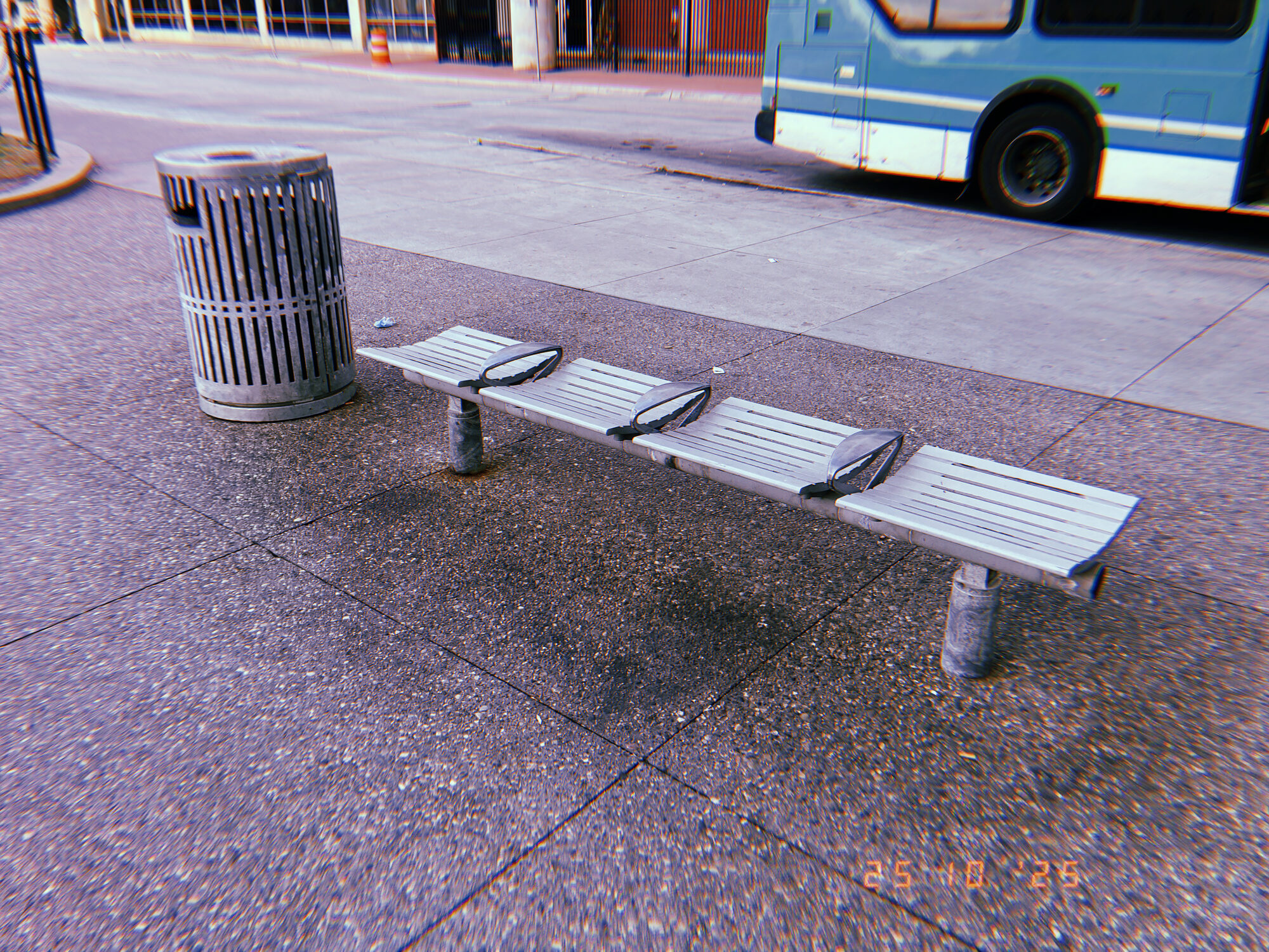 Bus stop bench and trash can on a downtown Detroit sidewalk as a bus pulls up