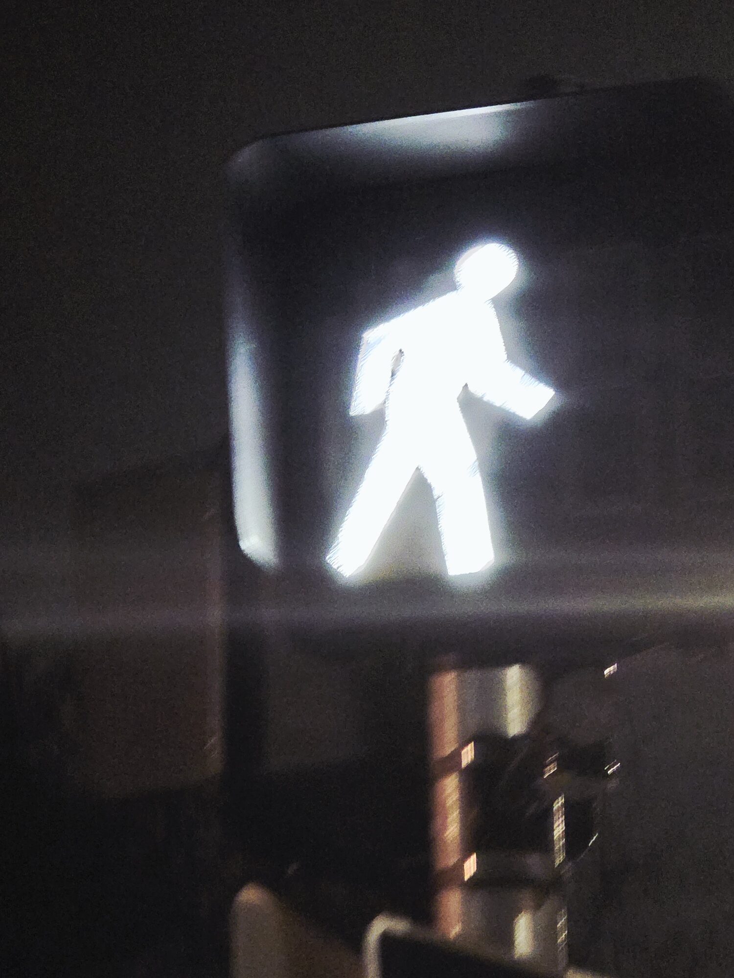 Glowing pedestrian crossing signal blurred with motion at night