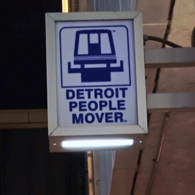 Glowing red Detroit People Mover station sign at night